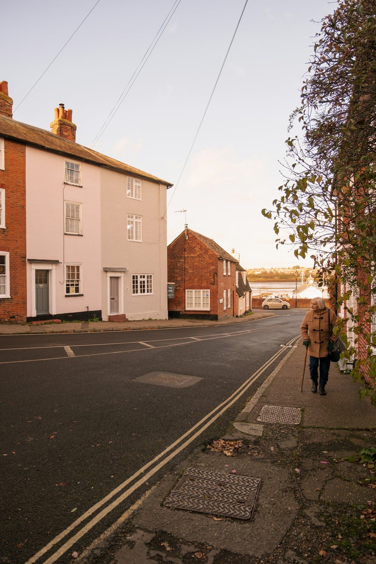 A woman walking down a street next to a tall brick building